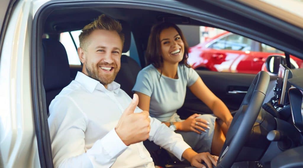 Couple sitting in their new car smiling