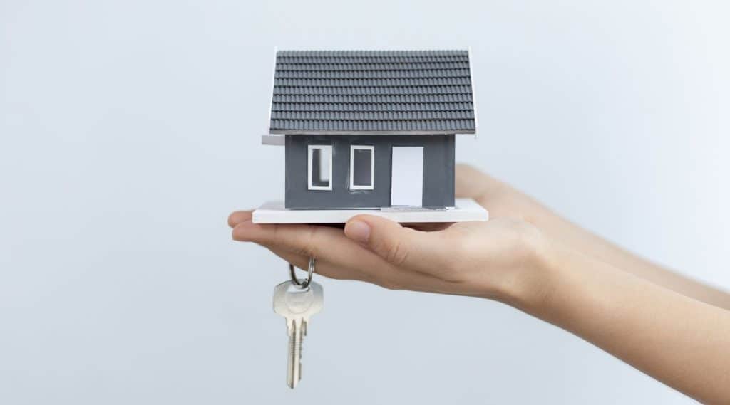 Close-up of person holding a model home and house keys