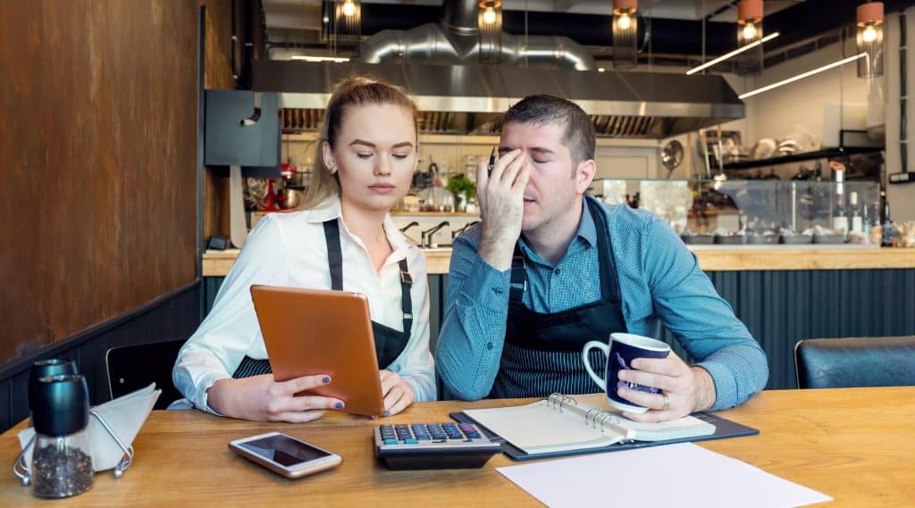 Female worker assisting her male coworker in a cafe with his finances