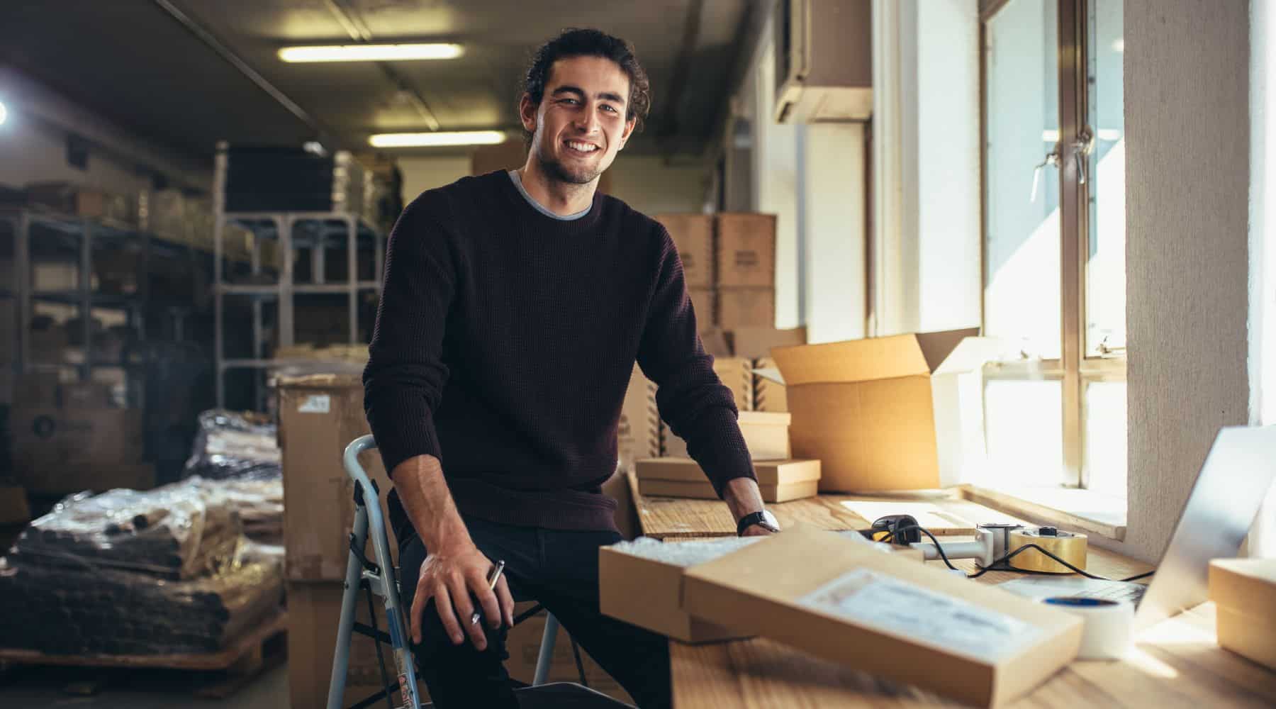 Man packing items into cardboard boxes for sending.