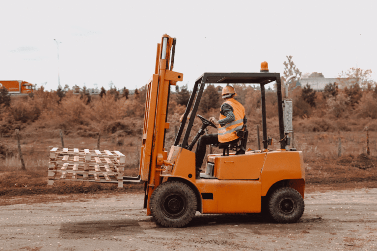 Man operating a forklift lifting wooden pallets